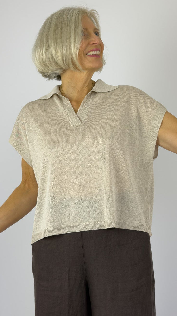 Woman wearing a beige sleeveless top and brown wide-leg pants on a plain background